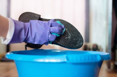 Eldivenli kadın ayakkabılarını sabunlu bir bezle temizliyor..