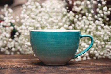 Çay fincanı ve çingene çiçekleri ahşap masa üzerinde yakın plan.