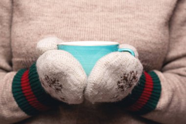 Sıcak kazaklı ve eldivenli kadın sıcak bir çay içiyor..