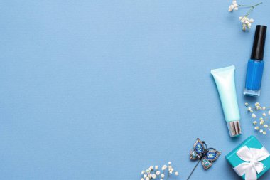 Tırnak cilası, dudak kremi ve mavi arka planda fotokopi alanı olan hediye kutusu..