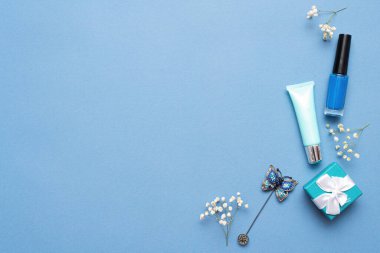 Tırnak cilası, dudak kremi ve mavi arka planda fotokopi alanı olan hediye kutusu..
