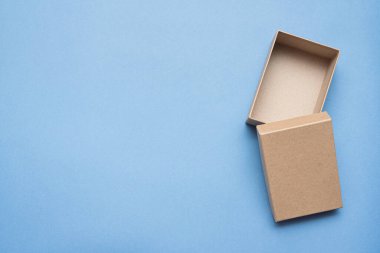 Mavi arkaplanda kahverengi, açık karton kutu.