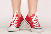 Nő láb piros gumicipő fehér háttér.