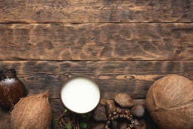 Fincanda hindistan cevizi sütü ve kahverengi tahta masa arkasında hindistan cevizi..