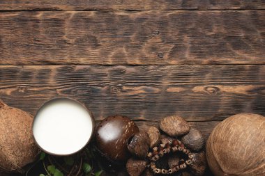 Fincanda hindistan cevizi sütü ve kahverengi tahta masa arkasında hindistan cevizi..