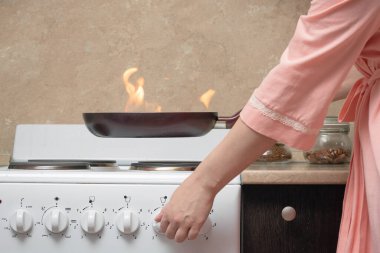 Şok olmuş bir kadın ve ev mutfağı kavramına ateş..