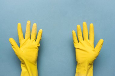 Sarı eldivenli kadın, mavi arkaplanda kopya alanı tutuyor..