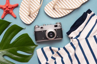 Kadın plaj kıyafetleri, terlik ayakkabılar ve mavi düz arka planda kırmızı denizyıldızı..