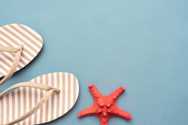 Flip flops ayakkabılar ve kırmızı denizyıldızı mavi düz arkaplan ile fotokopi alanı ile yatıyordu.