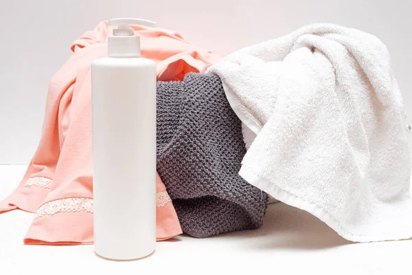 Detergent bottle, basin with dirty clothes on white background.