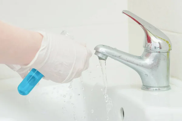 Musluk suyu analiz kalite kontrol kavramı. Elinde matara ve musluk musluğu olan bir el..