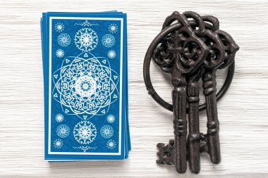 Mavi tarot kartları ve beyaz ahşap masa arka planındaki kaderin anahtarı. Kader kavramına ipucu.