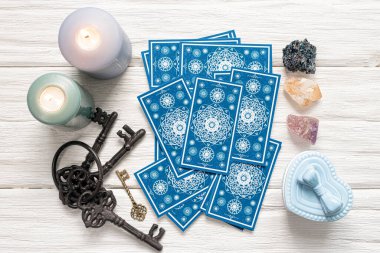 Mavi tarot kartları ve beyaz ahşap masa arka planındaki kaderin anahtarı. Kader kavramına ipucu.