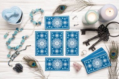 Mavi tarot kartları ve beyaz ahşap masa arka planındaki kaderin anahtarı. Kader kavramına ipucu.
