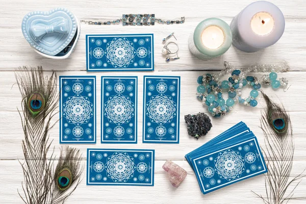 Beyaz ahşap masa arkasında mavi tarot kartları.