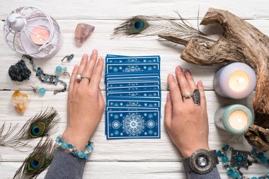 Falcı kadın ve beyaz ahşap masa üzerinde mavi tarot kartları..