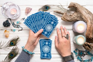 Falcı kadın ve beyaz ahşap masa üzerinde mavi tarot kartları..