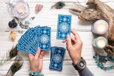 Falcı kadın ve beyaz ahşap masa üzerinde mavi tarot kartları..