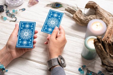 Falcı kadın ve beyaz ahşap masa üzerinde mavi tarot kartları..