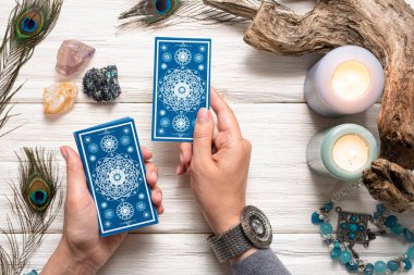 Falcı kadın ve beyaz ahşap masa üzerinde mavi tarot kartları..