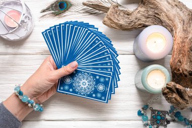 Falcı kadın ve beyaz ahşap masa üzerinde mavi tarot kartları..