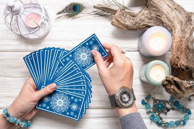 Falcı kadın ve beyaz ahşap masa üzerinde mavi tarot kartları..