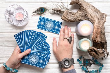 Falcı kadın ve beyaz ahşap masa üzerinde mavi tarot kartları..