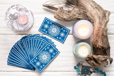Falcı kadın ve beyaz ahşap masa üzerinde mavi tarot kartları..