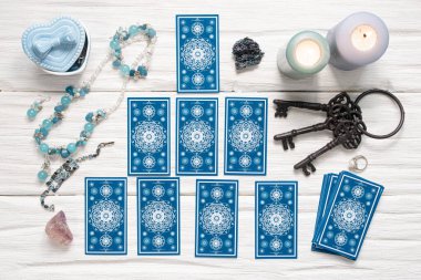 Mavi tarot kartları ve beyaz ahşap masa arka planındaki kaderin anahtarı. Kader kavramına ipucu.