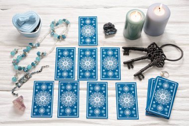 Mavi tarot kartları ve beyaz ahşap masa arka planındaki kaderin anahtarı. Kader kavramına ipucu.