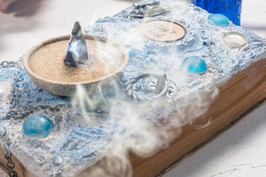 Beyaz bir arka planda beyaz büyü kitabı ve tütsü. Sihirbaz tablosu.