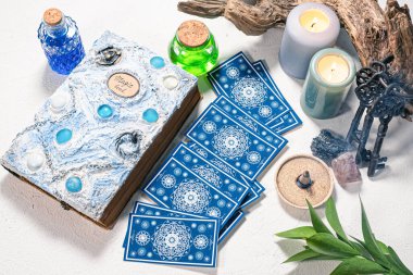 Tarot kartları ve beyaz masa arkasında beyaz büyü kitabı.