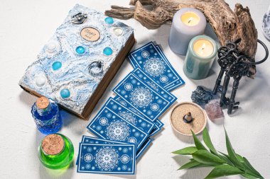 Tarot kartları, sihirli kitap ve iksir masada..