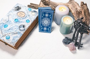 Tarot kartları ve beyaz masa arkasında beyaz büyü kitabı.