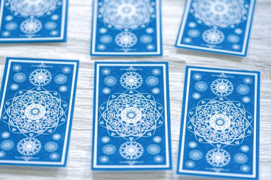 Beyaz ahşap masa arkasında mavi tarot kartları.
