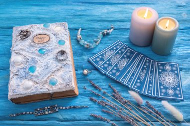 Mavi tarot kartları ve mavi ahşap masa zemininde beyaz sihirli kitap..