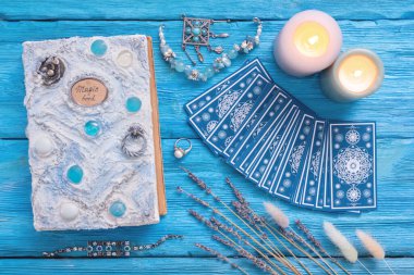 Mavi tarot kartları ve mavi ahşap masa zemininde beyaz sihirli kitap..