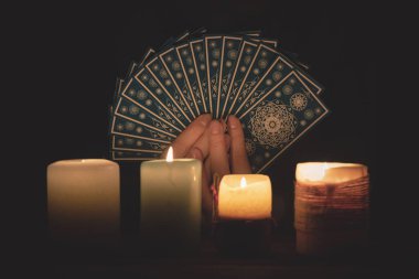 Falcı, mum ışığında tarot kartlarıyla geleceği okuyor..