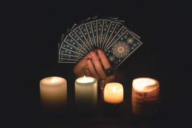 Falcı, mum ışığında tarot kartlarıyla geleceği okuyor..