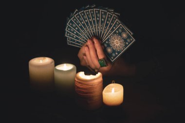 Falcı, mum ışığında tarot kartlarıyla geleceği okuyor..