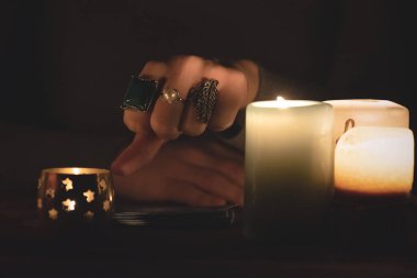 Falcı elini tarot kartlarının üstünde yüzüklerle gösteriyor..