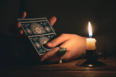 Falcı, mum ışığında tarot kartlarıyla geleceği okuyor..