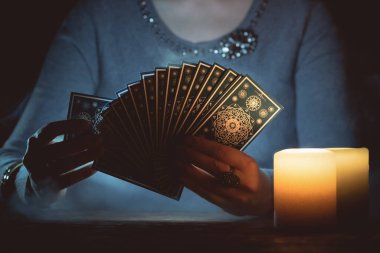 Elinde tarot kartları olan falcı yakın çekim yapıyor. Gelecek okuma konsepti.