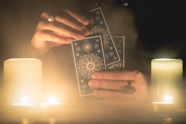 Elinde tarot kartları olan falcı yakın çekim yapıyor. Gelecek okuma konsepti.