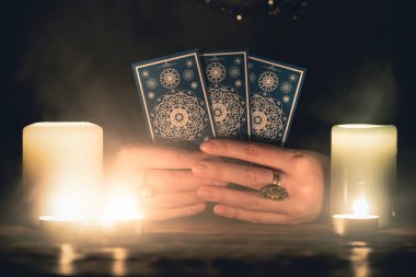 Elinde tarot kartları olan falcı yakın çekim yapıyor. Gelecek okuma konsepti.