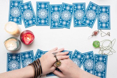 Falcı beyaz masa arka planında tarot kartlarında geleceği okuyor.