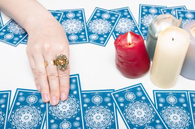 Falcı beyaz masa arka planında tarot kartlarında geleceği okuyor.