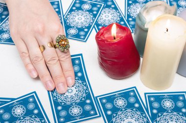 Falcı beyaz masa arka planında tarot kartlarında geleceği okuyor.