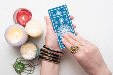 Falcı beyaz masa arka planında tarot kartlarında geleceği okuyor.