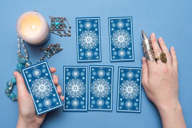 Falcı elinde tarot kartları tutuyor..